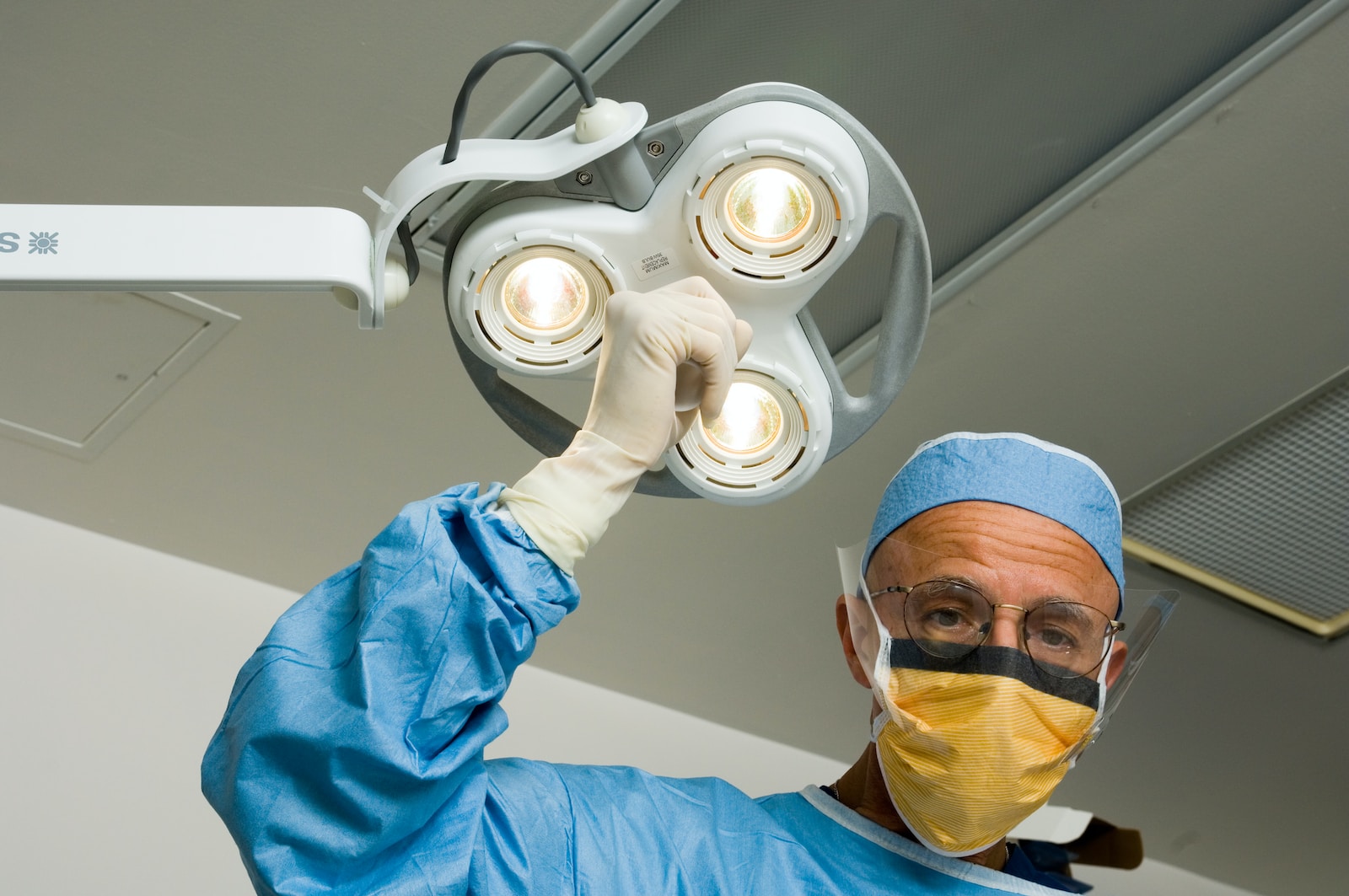 a man in a surgical gown holding up a surgical light